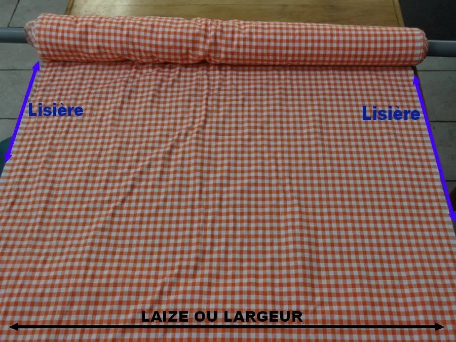 rouleau de tissu à carreaux vichy blanc et orange montrant la Laize et les lisieres